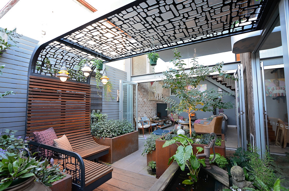 Foto di un piccolo patio o portico design dietro casa con un giardino in vaso, pedane e una pergola