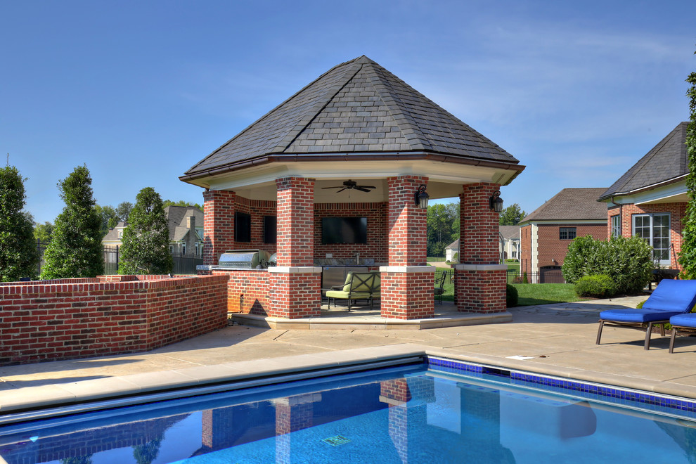 Cette image montre une grande terrasse arrière traditionnelle avec une cuisine d'été, des pavés en pierre naturelle et un gazebo ou pavillon.