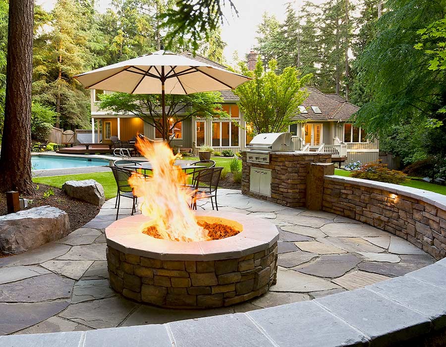 Large traditional back patio in Seattle with a fire feature and natural stone paving.