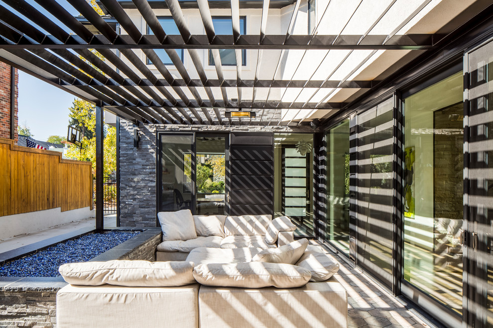Aménagement d'une grande terrasse latérale contemporaine avec un foyer extérieur, du carrelage et un auvent.