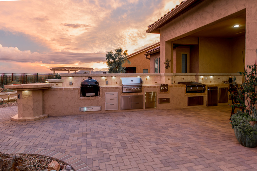 Large modern back patio in Phoenix with an outdoor kitchen, brick paving and no cover.