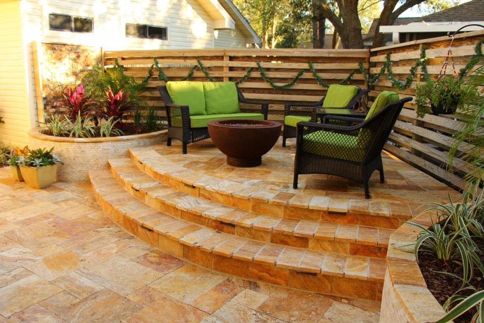 Immagine di un piccolo patio o portico tropicale dietro casa con un focolare e piastrelle