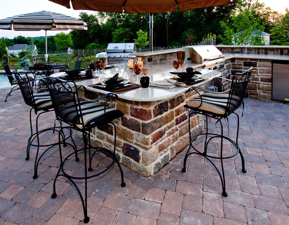 Large classic back patio in Other with a water feature, natural stone paving and an awning.