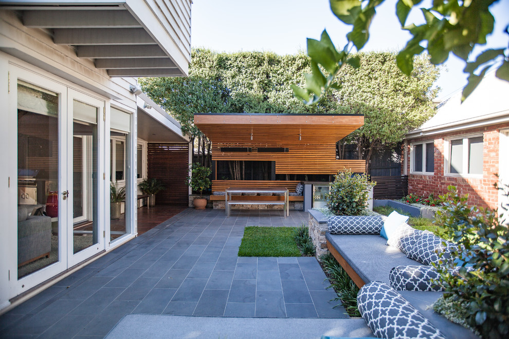 Immagine di un piccolo patio o portico design dietro casa con pavimentazioni in pietra naturale