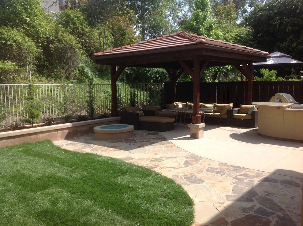 Photo of a large mediterranean back patio in San Diego with an outdoor kitchen, natural stone paving and a gazebo.