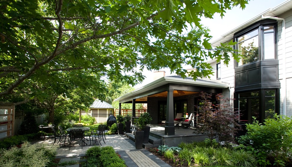 Immagine di un patio o portico design dietro casa e di medie dimensioni con un tetto a sbalzo e lastre di cemento