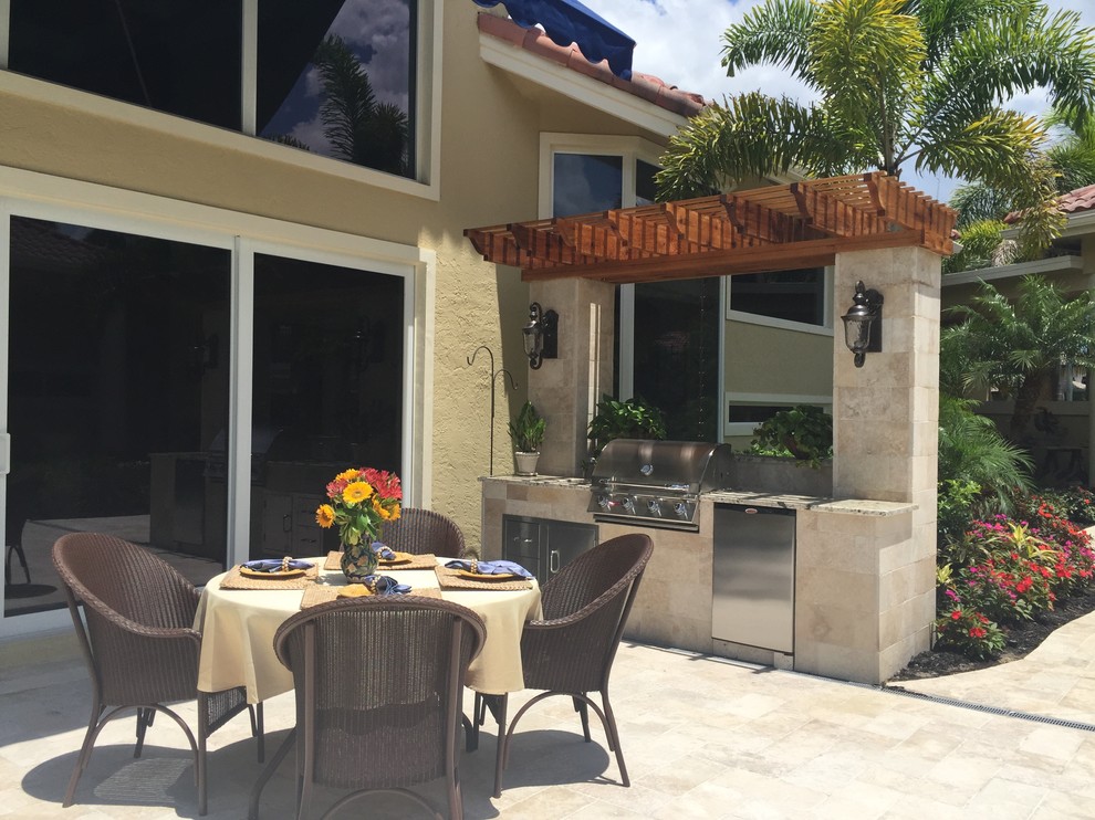 Mid-sized island style courtyard stone patio kitchen photo in Miami with a pergola