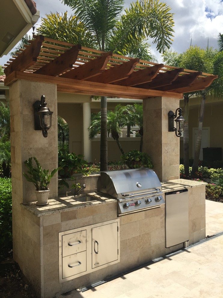 Exemple d'une terrasse exotique de taille moyenne avec une cuisine d'été, une cour, des pavés en pierre naturelle et une pergola.