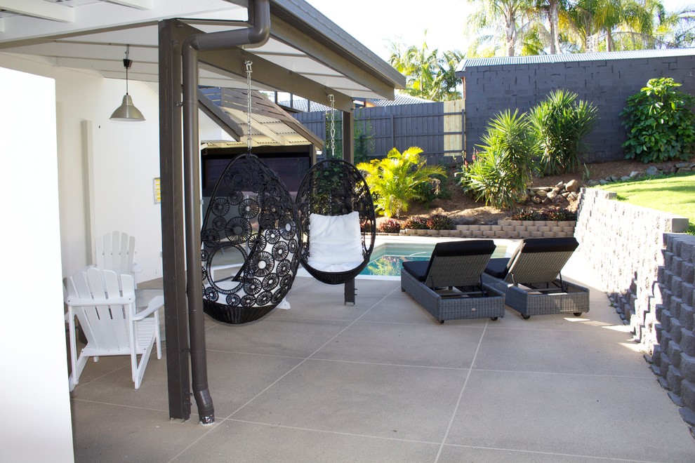 Foto di un patio o portico tropicale di medie dimensioni e dietro casa con pavimentazioni in cemento e una pergola