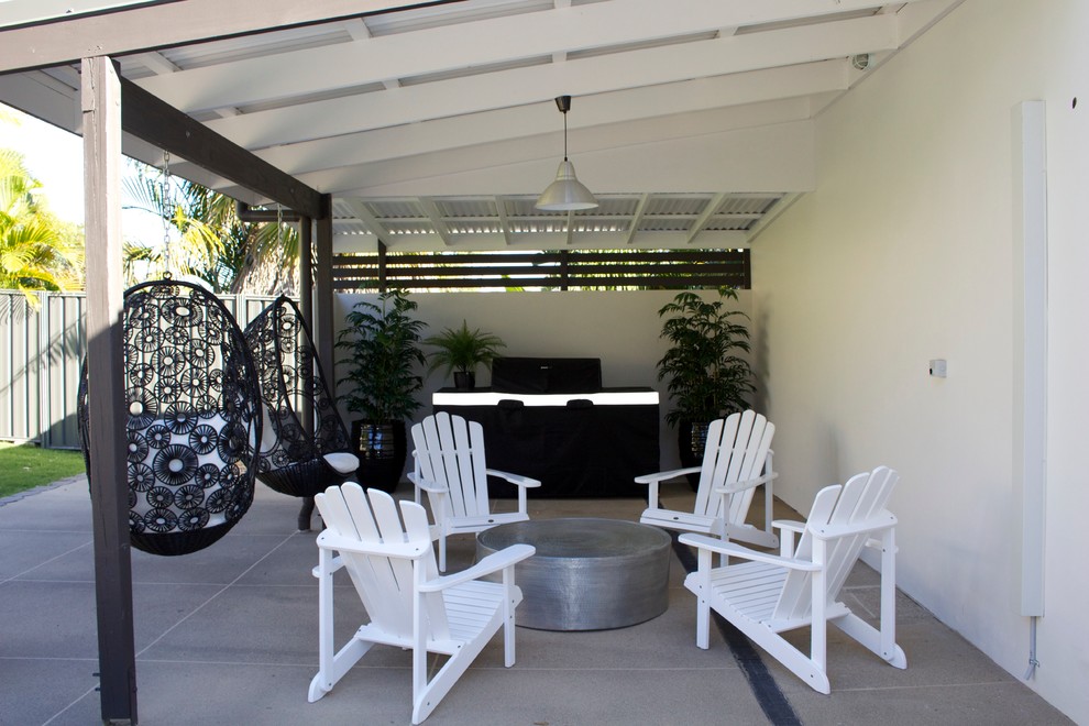 Ispirazione per un patio o portico tropicale di medie dimensioni e dietro casa con pavimentazioni in cemento e una pergola