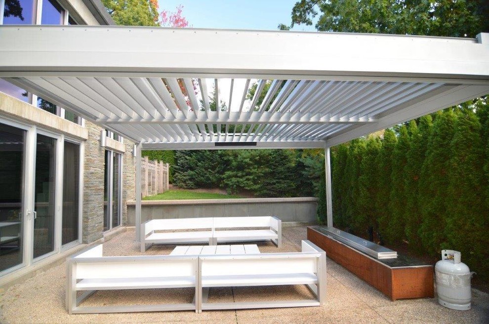 Example of a mid-sized trendy backyard decomposed granite patio design in Other with a pergola