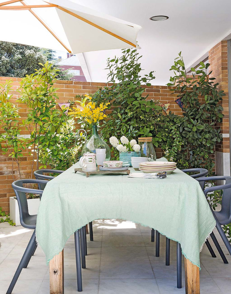 Réalisation d'une terrasse avec des plantes en pots arrière méditerranéenne de taille moyenne avec du carrelage et une extension de toiture.