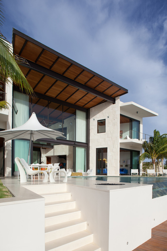 Idée de décoration pour une terrasse arrière design avec un foyer extérieur et une extension de toiture.
