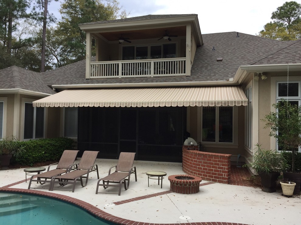 Immagine di un patio o portico classico di medie dimensioni e dietro casa con lastre di cemento e un parasole