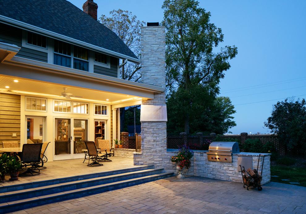 Inspiration pour une terrasse arrière traditionnelle avec un foyer extérieur, des pavés en béton et une extension de toiture.