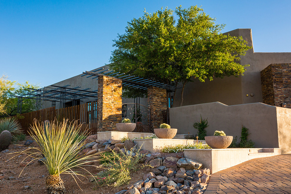 This is an example of a medium sized industrial back patio in Phoenix with a potted garden and a pergola.