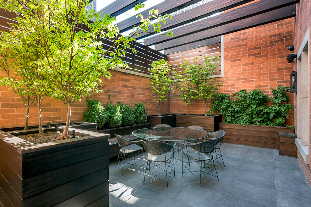 Imagen de patio contemporáneo con suelo de baldosas y pérgola