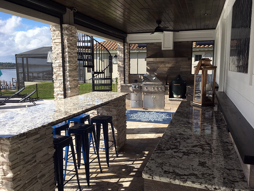 Immagine di un grande patio o portico chic dietro casa con un caminetto, pavimentazioni in pietra naturale e un tetto a sbalzo