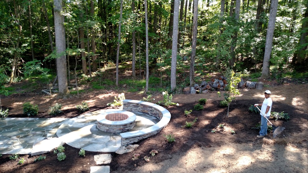 Example of a mid-sized mountain style backyard stone patio design in Raleigh with a fire pit and no cover