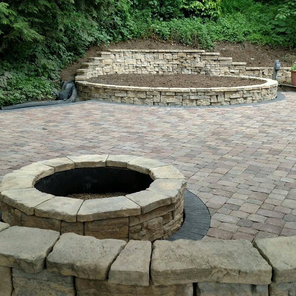 Photo of a large rustic back patio in Other with a fire feature and concrete paving.