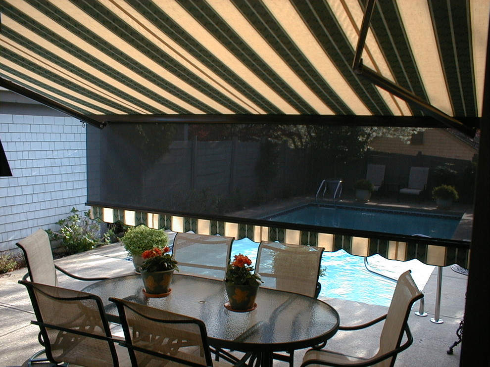 Medium sized back patio in Boston with concrete slabs and an awning.