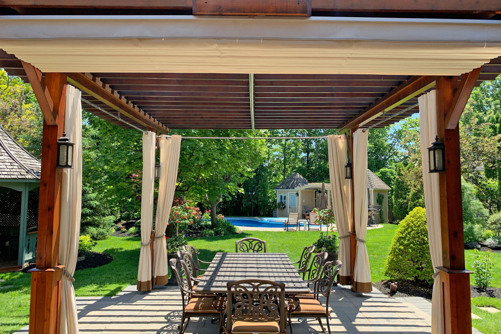 Immagine di un patio o portico tradizionale dietro casa con pavimentazioni in cemento e una pergola