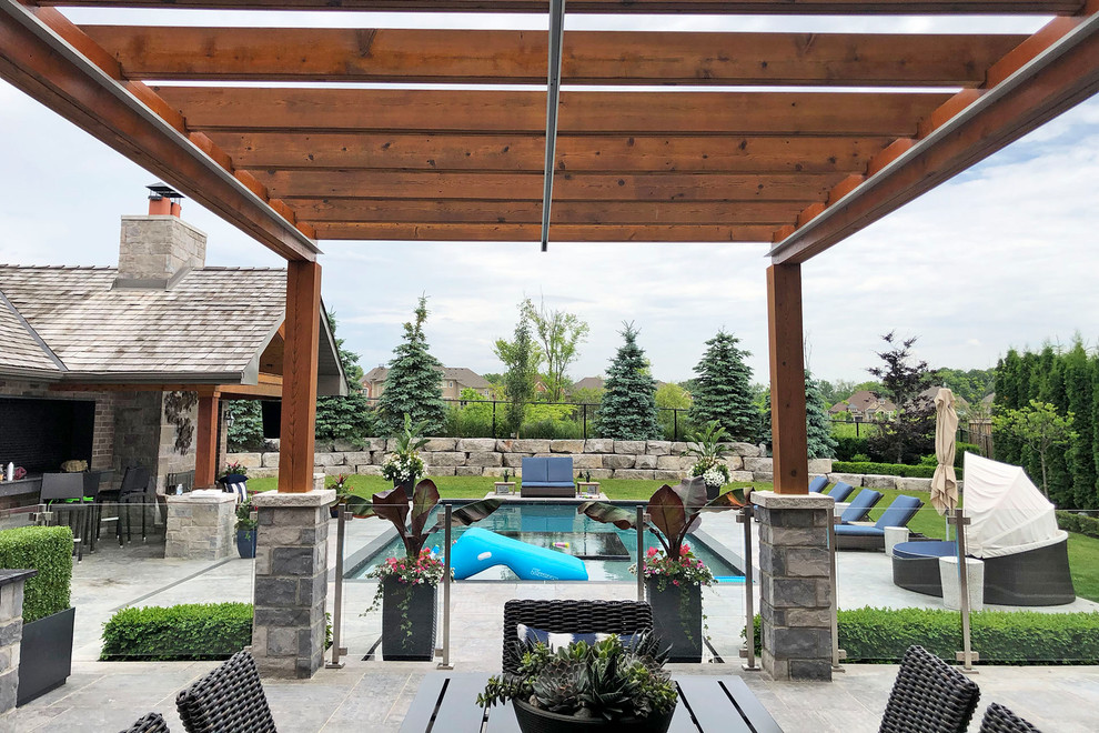 This is an example of a contemporary back patio in Toronto with concrete paving and a pergola.