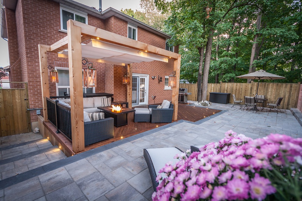 Diseño de patio clásico en patio trasero con adoquines de hormigón y pérgola