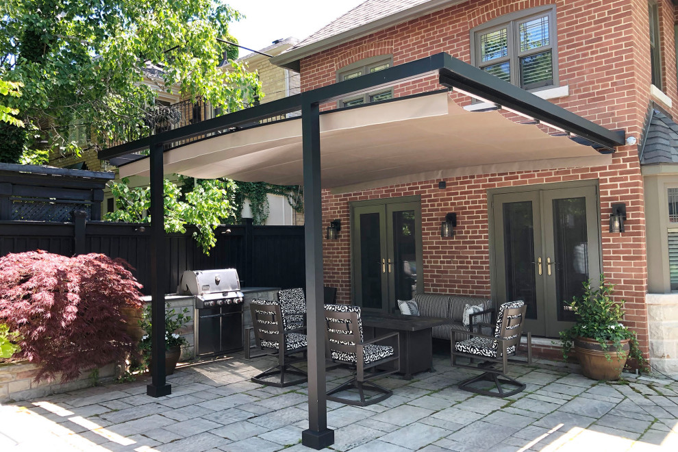 Modern back patio in Toronto with concrete paving and a pergola.