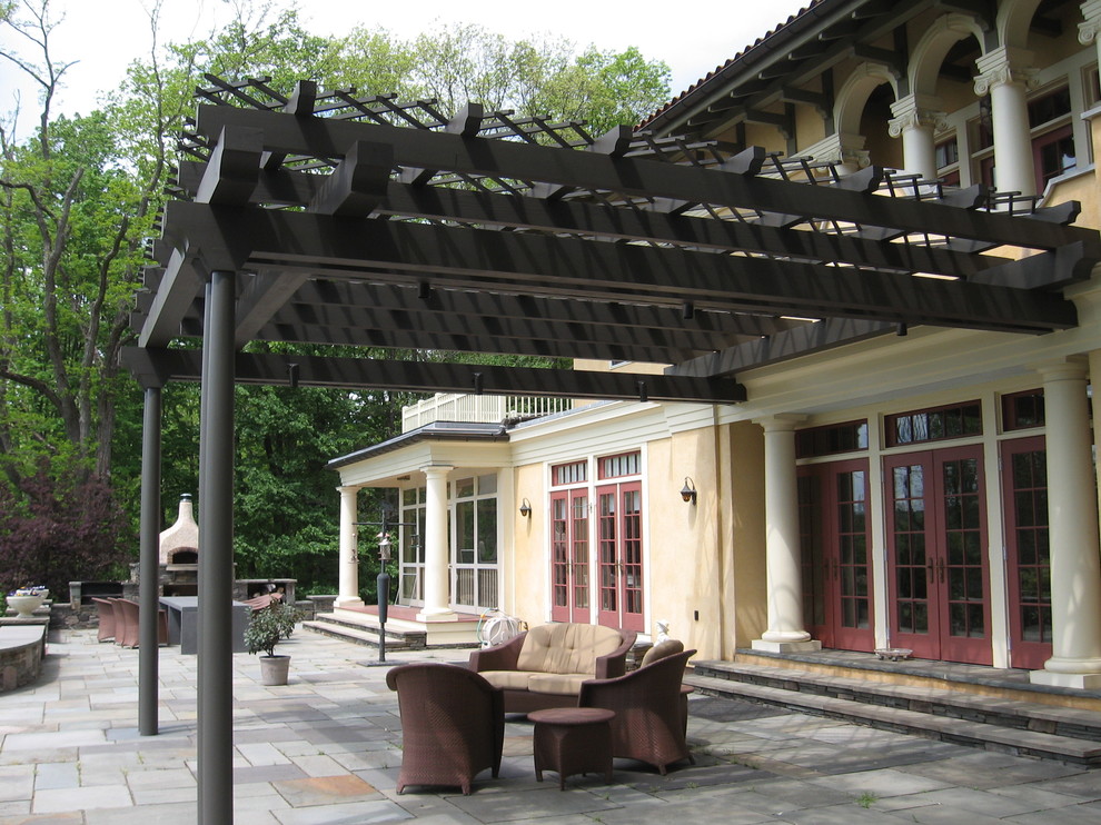 Esempio di un ampio patio o portico dietro casa con un focolare, pavimentazioni in pietra naturale e una pergola
