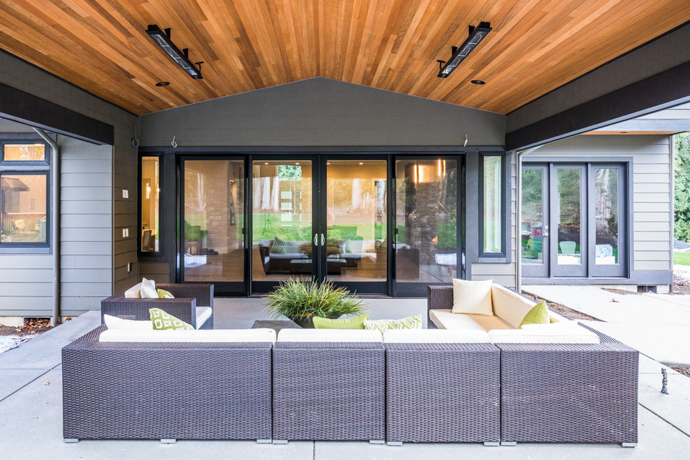 Inspiration for a modern back patio in Seattle with concrete paving and a roof extension.