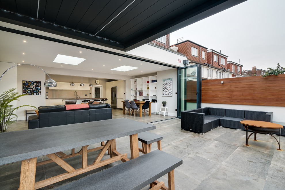 Foto de patio contemporáneo de tamaño medio en patio trasero con adoquines de piedra natural y toldo