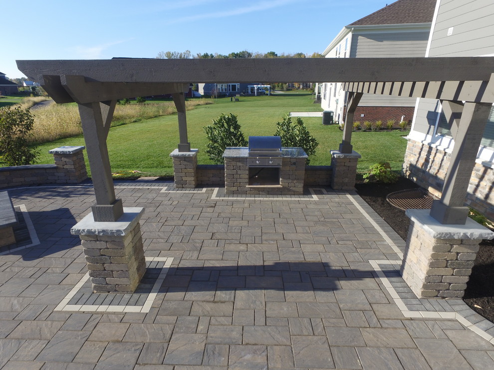 Large contemporary back patio in Columbus with an outdoor kitchen, brick paving and a pergola.