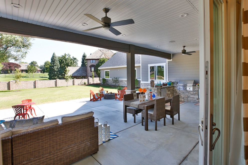 Cette image montre une grande terrasse arrière traditionnelle avec une cuisine d'été, une dalle de béton et une extension de toiture.