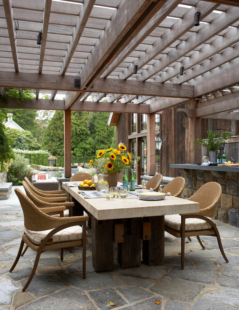 Imagen de patio de estilo de casa de campo en patio trasero con adoquines de piedra natural y pérgola