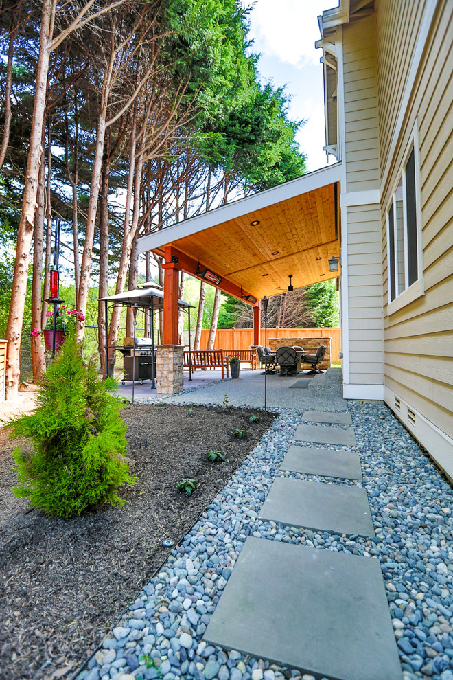 Esempio di un patio o portico stile americano di medie dimensioni e dietro casa con un caminetto, pavimentazioni in cemento e un tetto a sbalzo