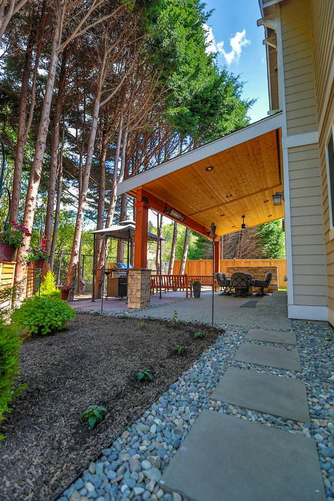 Idee per un patio o portico american style di medie dimensioni e dietro casa con un caminetto, pavimentazioni in cemento e un tetto a sbalzo
