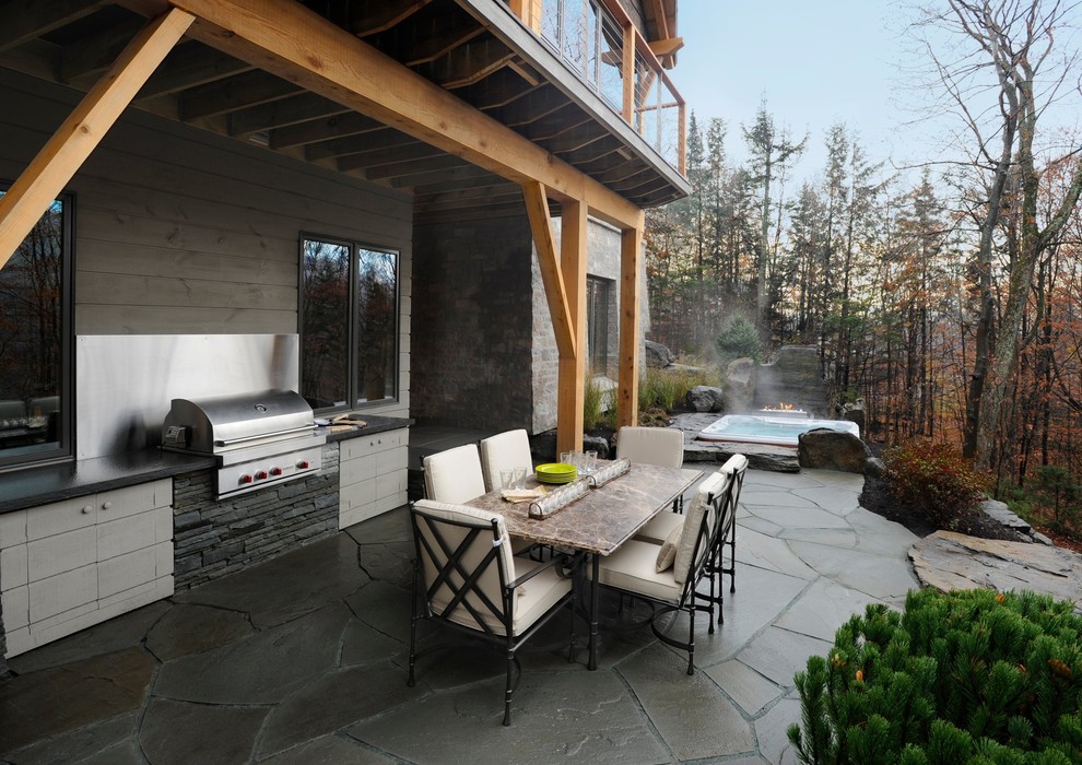 Cette photo montre une grande terrasse arrière montagne avec une cuisine d'été, du béton estampé et une extension de toiture.