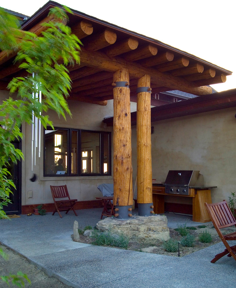 Immagine di un patio o portico etnico di medie dimensioni e in cortile con lastre di cemento e un parasole