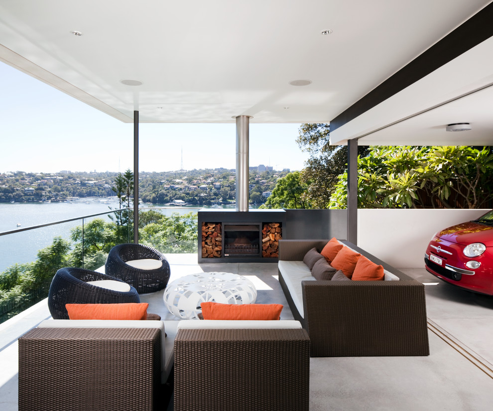Aménagement d'une terrasse contemporaine avec un foyer extérieur, une dalle de béton et une extension de toiture.
