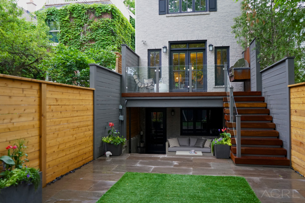 This is an example of a contemporary back patio in Toronto with natural stone paving.