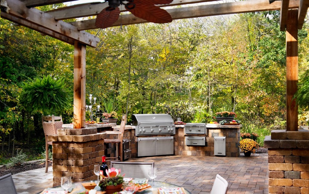 Inspiration for a large rustic backyard brick patio kitchen remodel in Other with a pergola