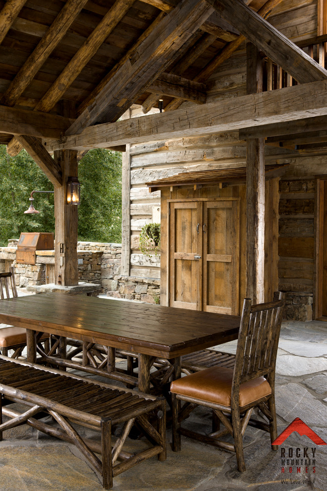 Mid-sized mountain style side yard stone patio kitchen photo in Other with a roof extension