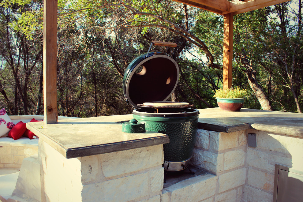 Photo of a medium sized contemporary back patio in Austin with an outdoor kitchen, natural stone paving and a pergola.