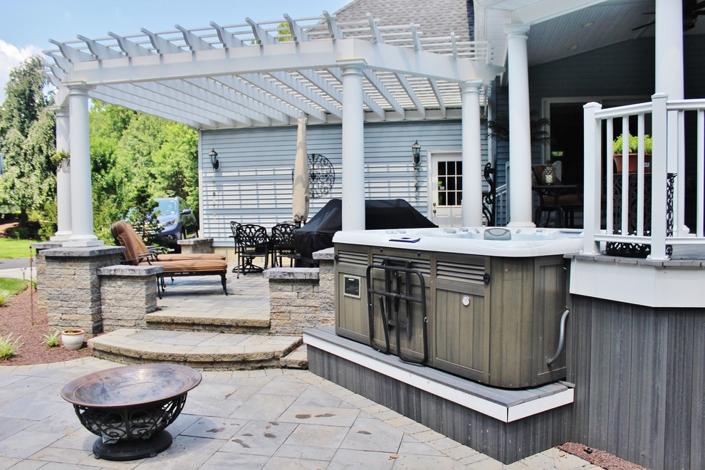 Photo of a large classic back patio in Philadelphia with a water feature, natural stone paving and a roof extension.