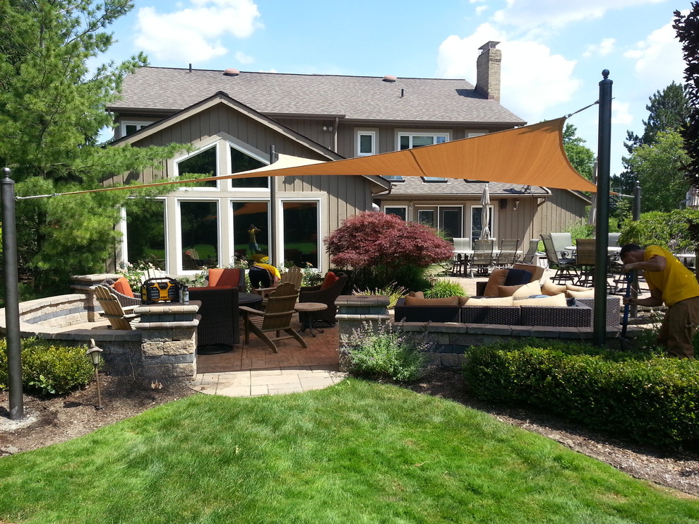 Cette image montre une grande terrasse arrière design avec une cuisine d'été, du béton estampé et un auvent.
