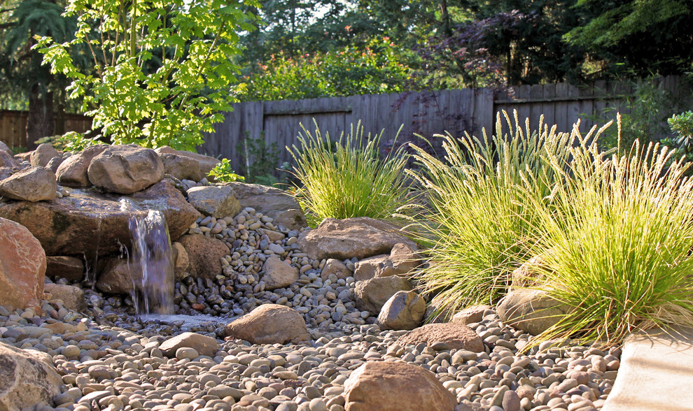 Mid-sized trendy backyard gravel patio fountain photo in Other