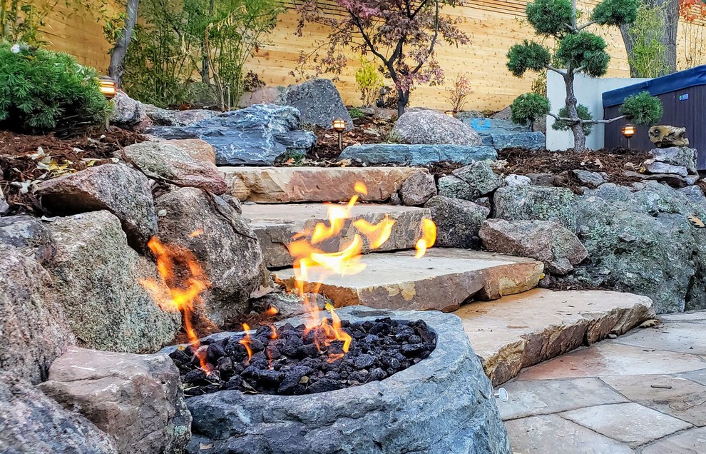 Ejemplo de patio de estilo zen grande en patio trasero con brasero y adoquines de piedra natural