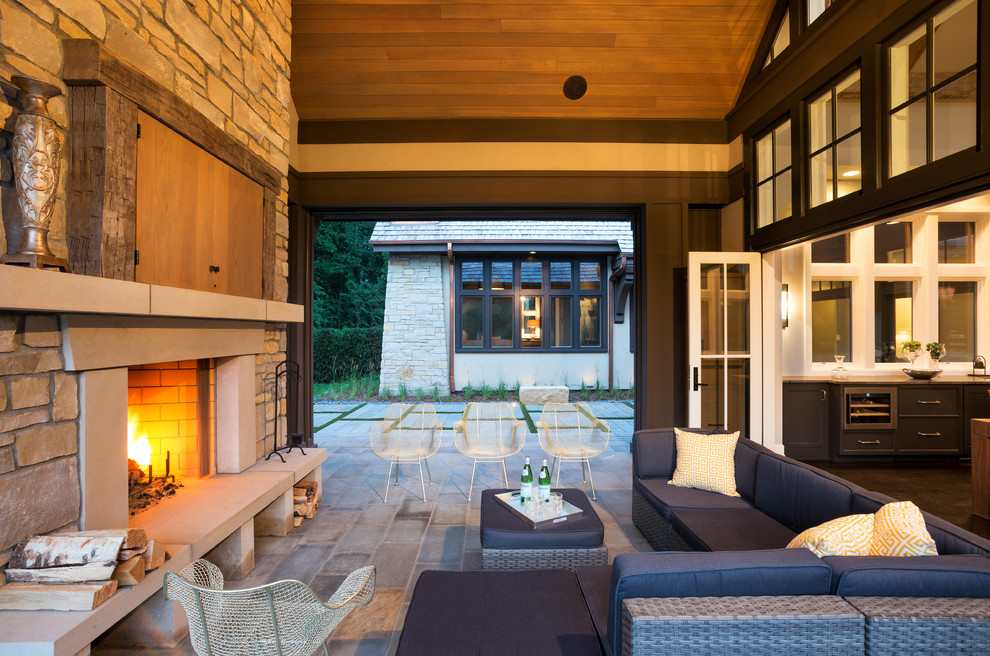 Example of a transitional backyard stone patio design in Minneapolis with a roof extension and a fireplace