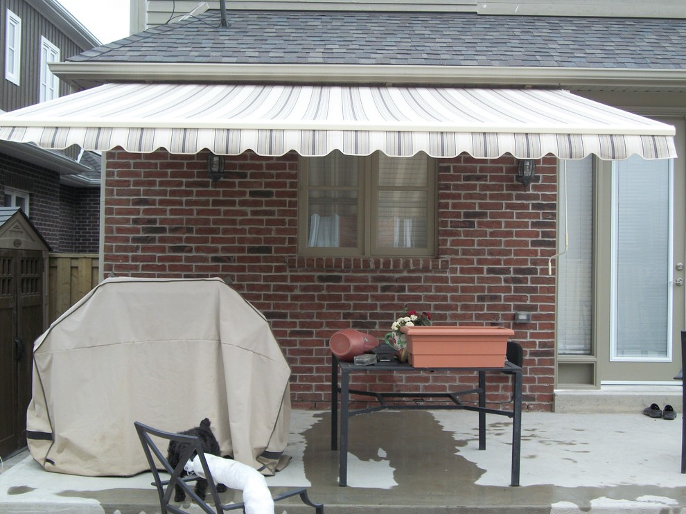 Photo of a small classic back patio in Calgary with concrete slabs and an awning.